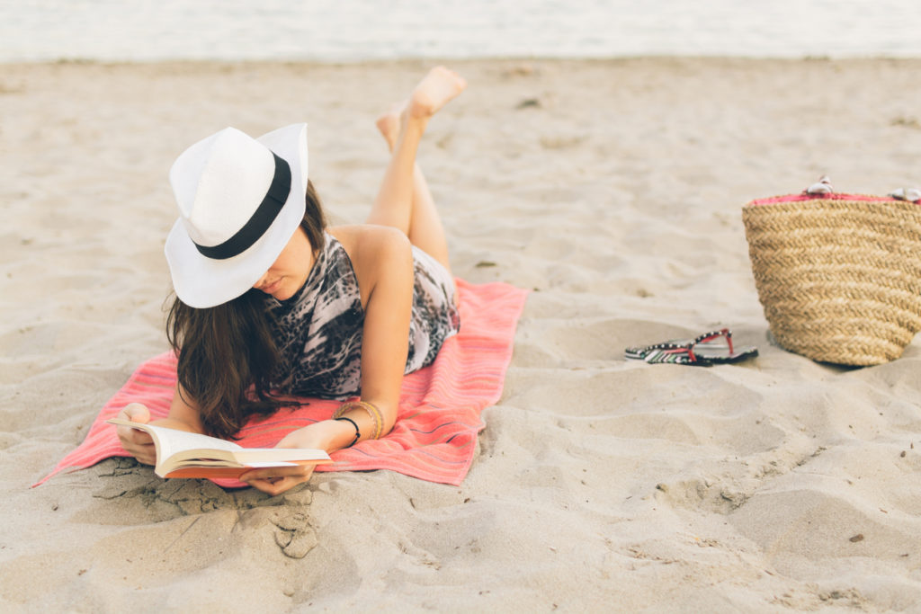 ragazza sulla spiaggia che legge un libro