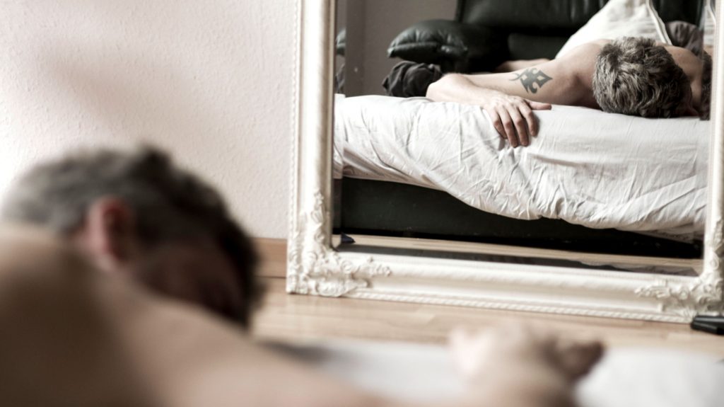 uomo che dorme davanti allo specchio